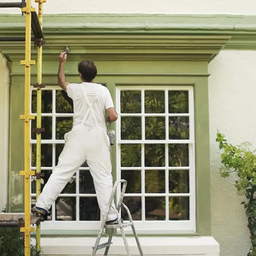 a painter is doing exterior painting upon a window