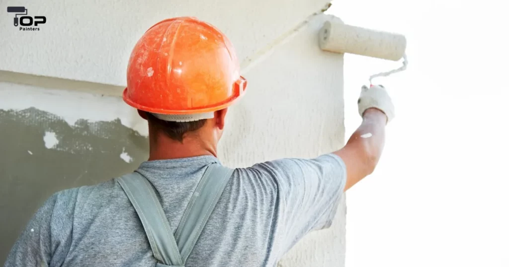 A man using a roller to paint a building exterior.